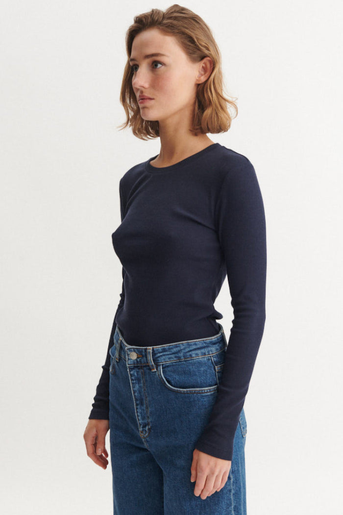 Basic Apparel Ludmilla LS Tee i sky captain – tætsiddende bluse i økologisk bomuld med ribstruktur, lange ærmer og afrundet hals.
