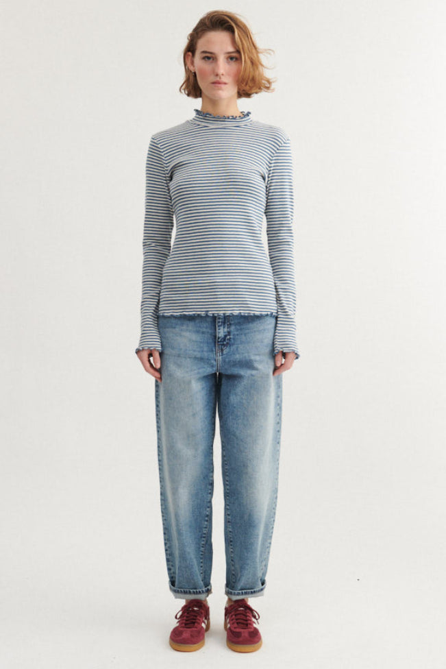 Basic Apparel Silma High Neck i copen blue/birch – tætsiddende bluse i økologisk bomuld med høj krave, lange ærmer og bølgede kanter.

