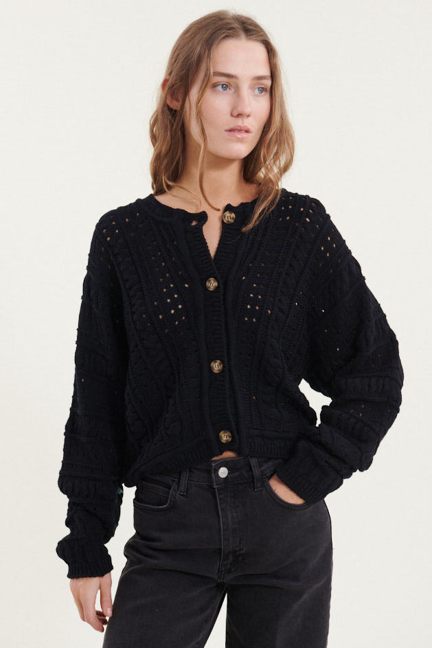 Basic Apparel Winie Cardigan i sort med strikket mønster, stolpelukning og rund hals i økologisk bomuld.

