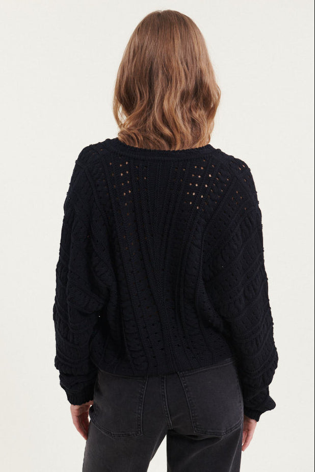 Basic Apparel Winie Cardigan i sort med strikket mønster, stolpelukning og rund hals i økologisk bomuld.
