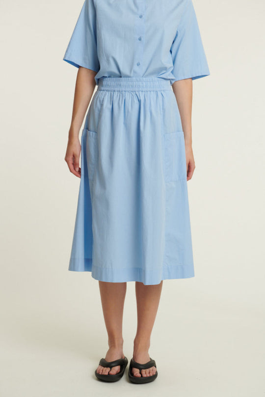 Basic Apparel Silje Skirt i frozen fjord med elastik i taljen, sidelommer og knælængde i økologisk bomuld.
