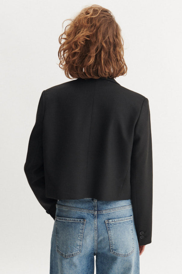 Basic Apparel Radi Short Jakke i sort – let, dobbeltradet jakke i genanvendt polyester med reverskrave og løs pasform.
