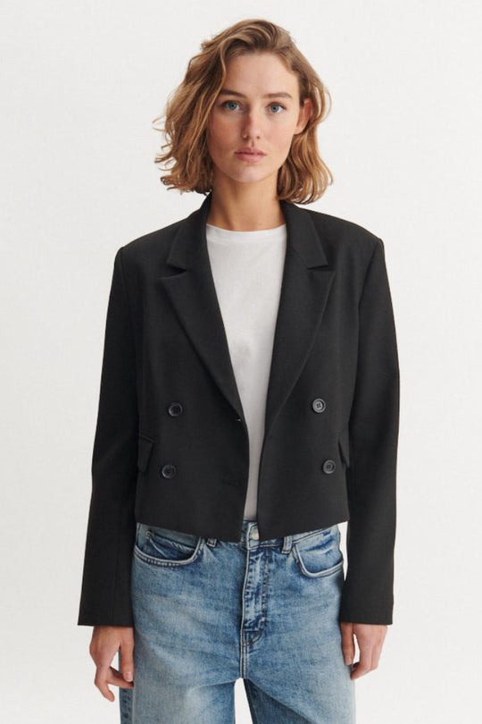 Basic Apparel Radi Short Jakke i sort – let, dobbeltradet jakke i genanvendt polyester med reverskrave og løs pasform.
