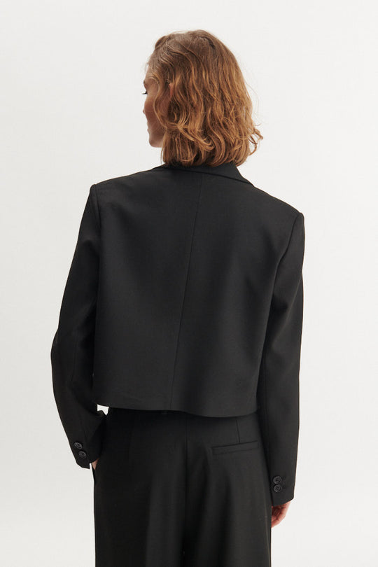 Basic Apparel Radi Short Jakke i sort – let, dobbeltradet jakke i genanvendt polyester med reverskrave og løs pasform.
