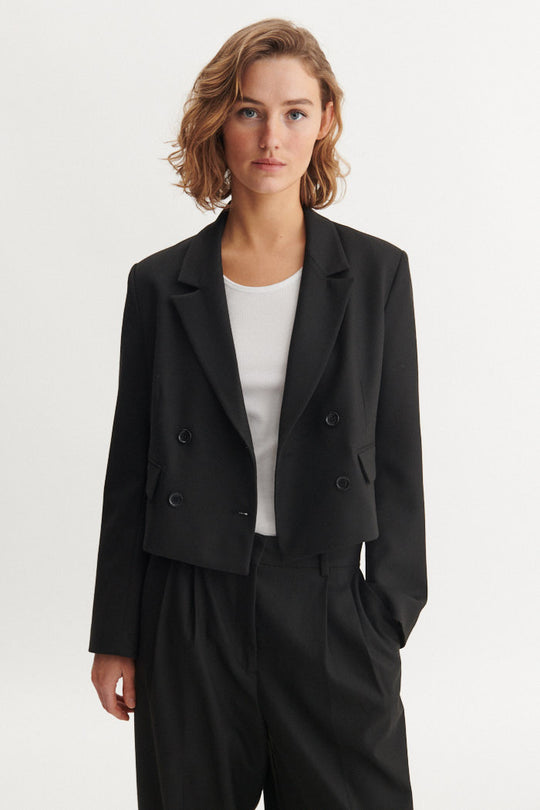 Basic Apparel Radi Short Jakke i sort – let, dobbeltradet jakke i genanvendt polyester med reverskrave og løs pasform.
