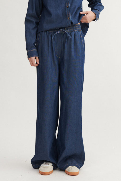 Basic Apparel Bine Wide Pant i Mid Blue, brede bukser med elastik i taljen og skrålommer. Fremstillet af TENCEL™ og økologisk bomuld.