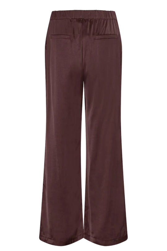 Continue Roberta Satin bukser i bordeaux med vide ben, elastik i taljen, skrålommer og satinfinish.
