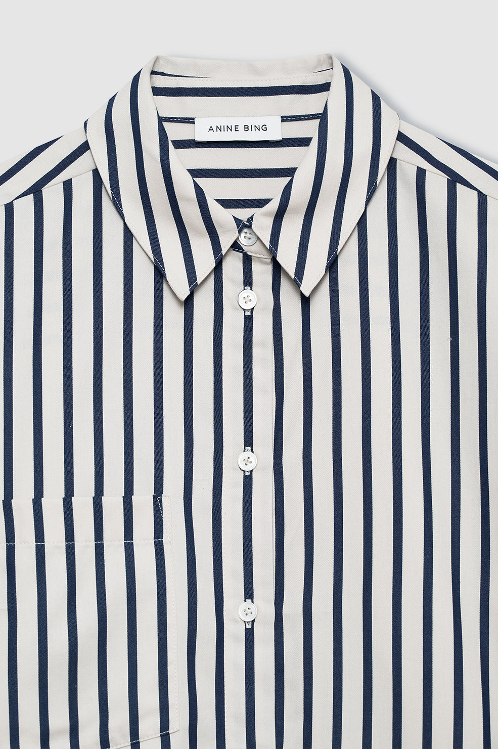 Anine Bing Essie Cropped Shirt i Maritime Stripe – cropped bomuldsskjorte med navy og tan striber, boxy pasform og klassiske knapper.
