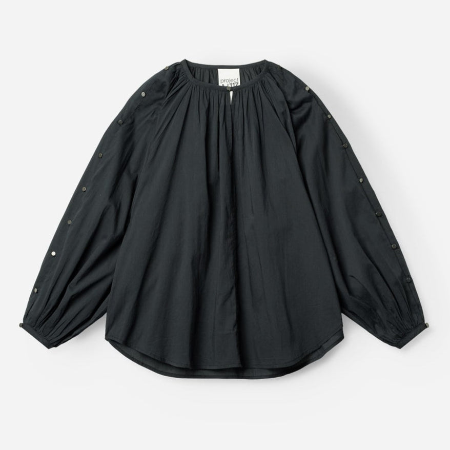 Project AJ117 Hester Bluse i Black – feminin skjorte med gathered hals, raglanærmer, dekorative knapper og afrundet kant, fremstillet i 100% økologisk bomuldsvoile.

