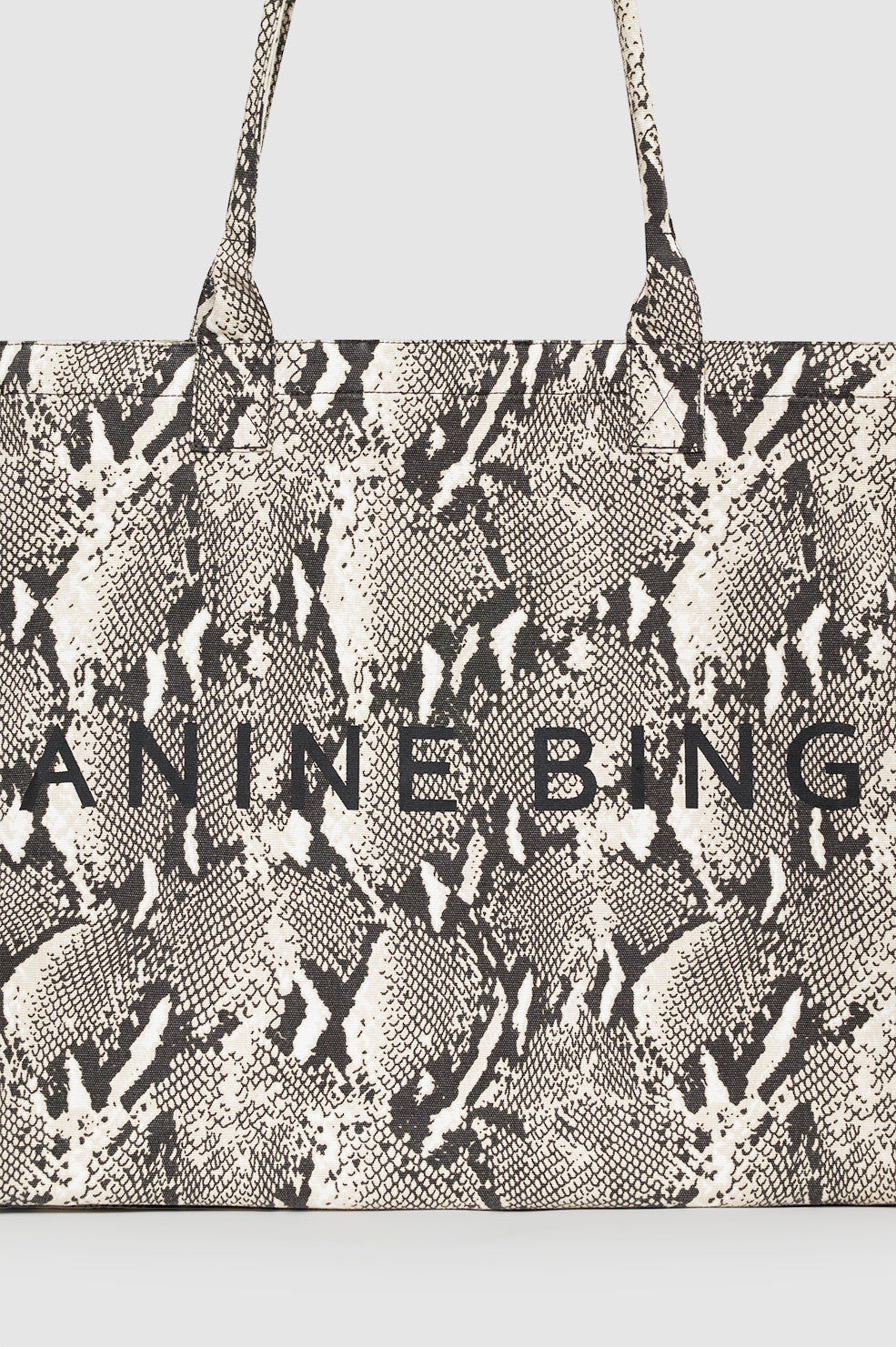 Anine Bing Leo Canvas Tote i python-print – rummelig canvas-taske med sorte og hvide pythonmønster og Anine Bing screen-trykt logo.

