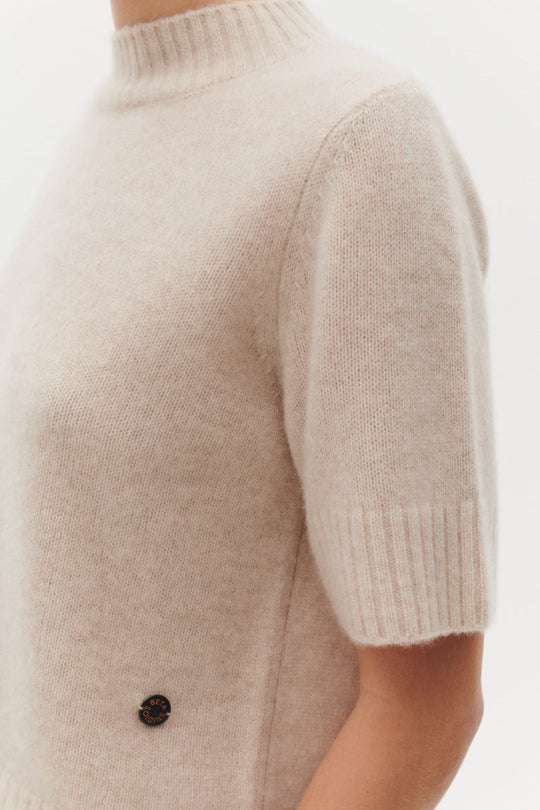 Beta Studios Mie Short Sleeves strikbluse i Eco Alabast White – kort cashmere top med turtleneck og brede ribbede kanter.
