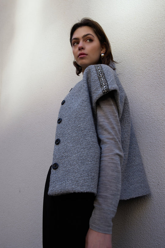 PBO Kino Cape i light grey – kort cape med rund hals og perle-detaljer over skuldrene.
