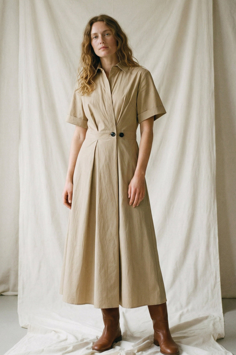 La Rouge Pia kjole i sand med V-udskæring, korte ærmer og asymmetrisk knaplukning.