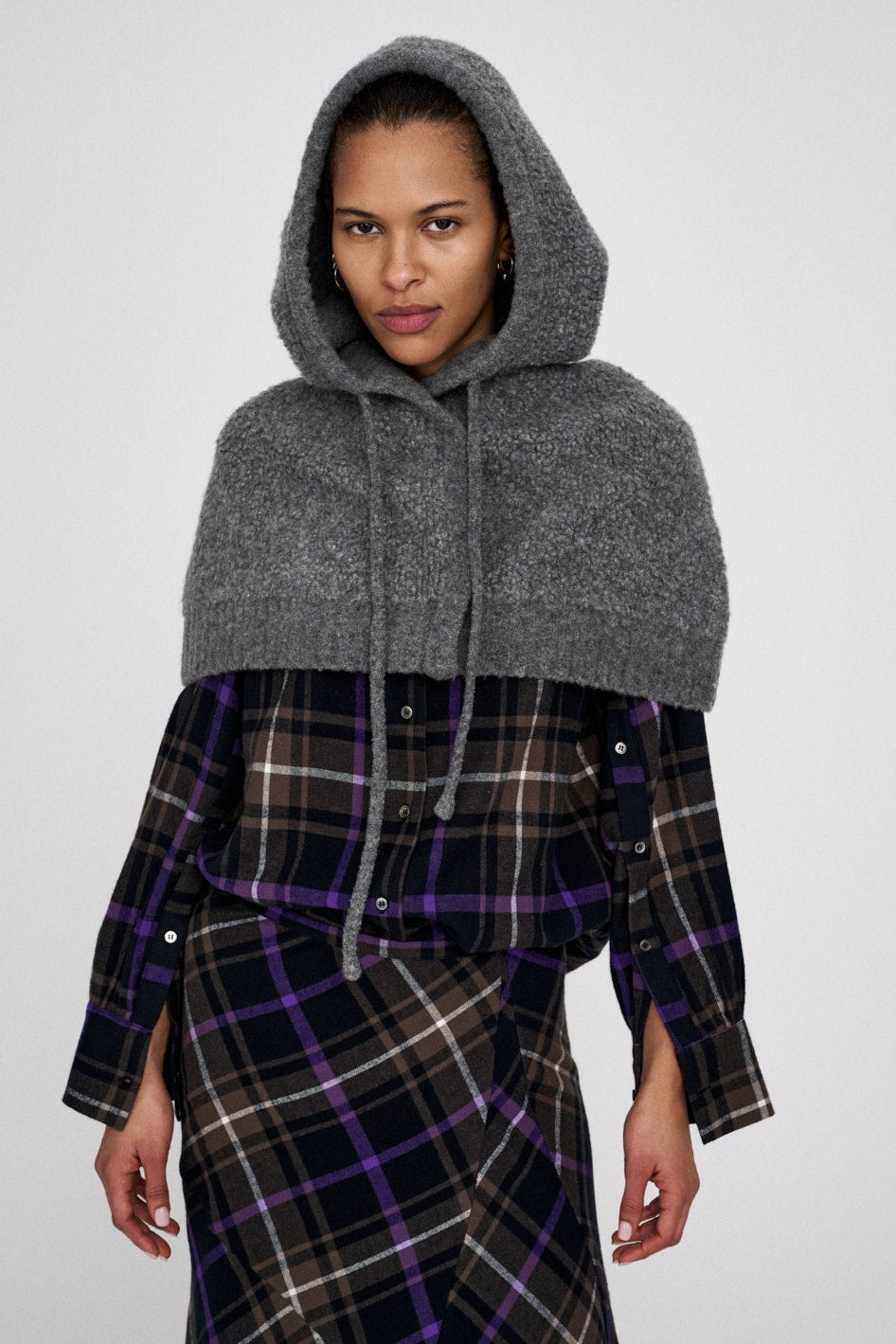 Sinika Sheep Knit Hood i grå med oversized hætte, knaplukning foran og snoretræk – uldblandet hue/hætte til både praktisk og dekorativ brug.
